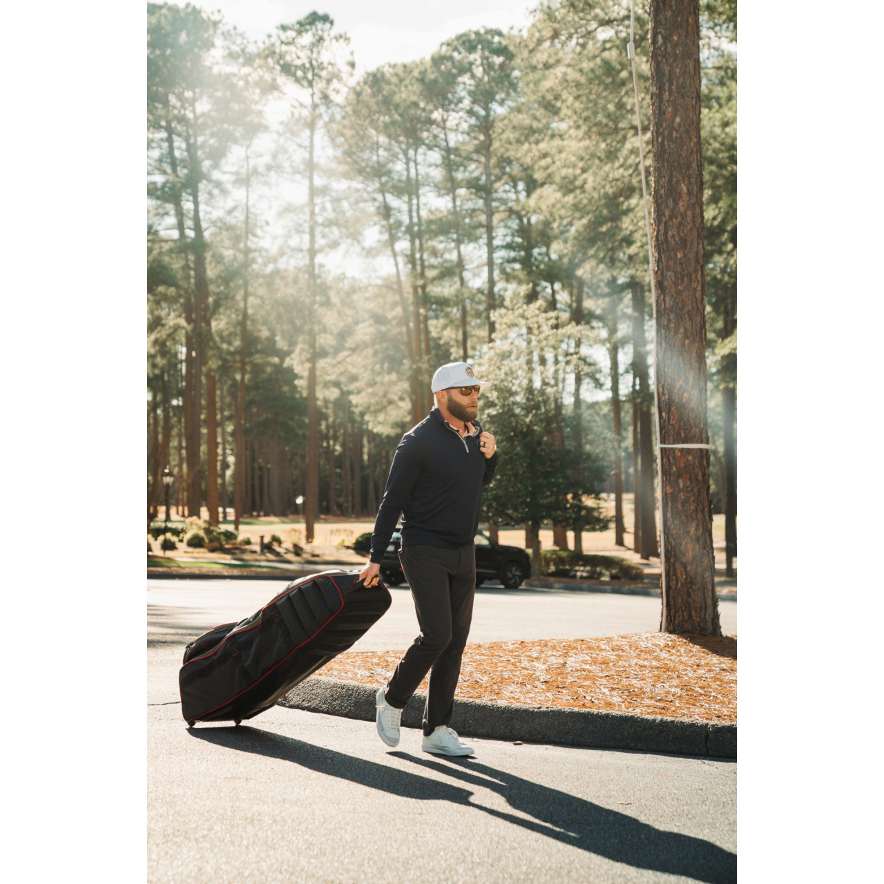 Bag Boy T-800 lifestyle photo showing spinner wheels and carry handle in use